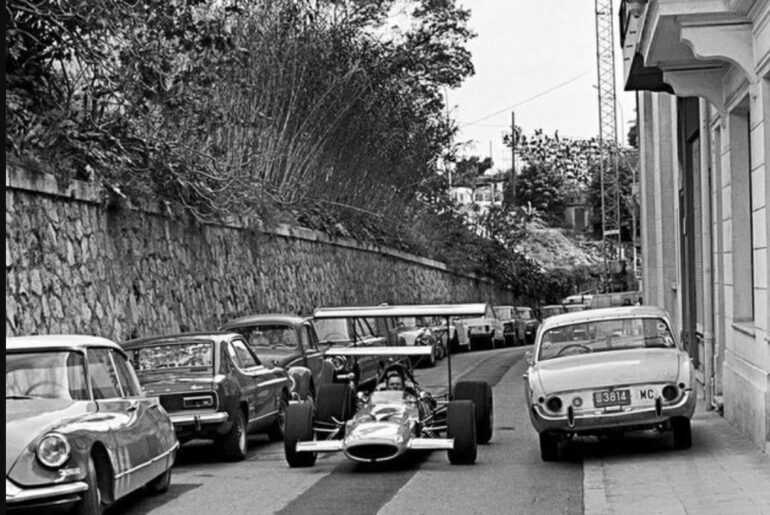 Bruce McLaren in his McLaren M7C making his way through the Monaco streets to the urban circuit for the Thursday qualifying. 1969 Monaco GP. On the left also a Citroen DS, on the right a European Ford Taunus 17M (1034x1120)